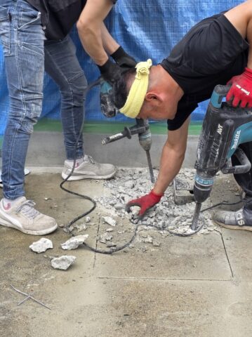 職人さんが床のコンクリートをハツリ、土を掘り起こして散水栓を立水栓へ変更する工事をしているリアルな作業写真