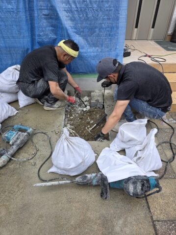職人さんが床のコンクリートをハツリ、土を掘り起こして散水栓を立水栓へ変更する工事をしているリアルな作業写真