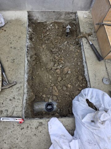 掘り起こした土の中から給水管を見つけ出し、新しい立水栓へ繋ぐための確実な配管処理を行っている手元の写真