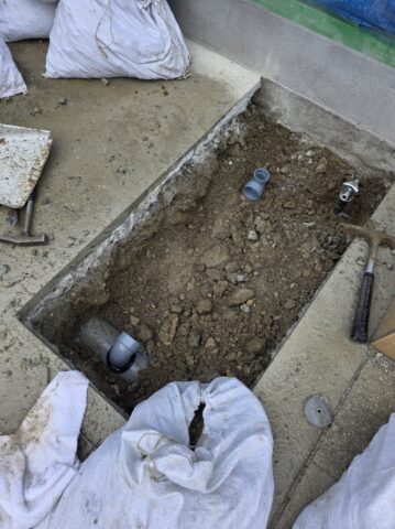 掘り起こした土の中から給水管を見つけ出し、新しい立水栓へ繋ぐための確実な配管処理を行っている手元の写真
