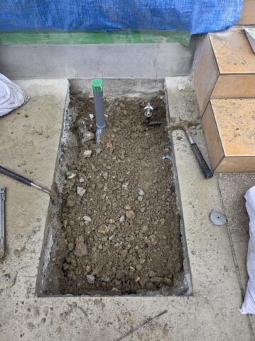 掘り起こした土の中から給水管を見つけ出し、新しい立水栓へ繋ぐための確実な配管処理を行っている手元の写真